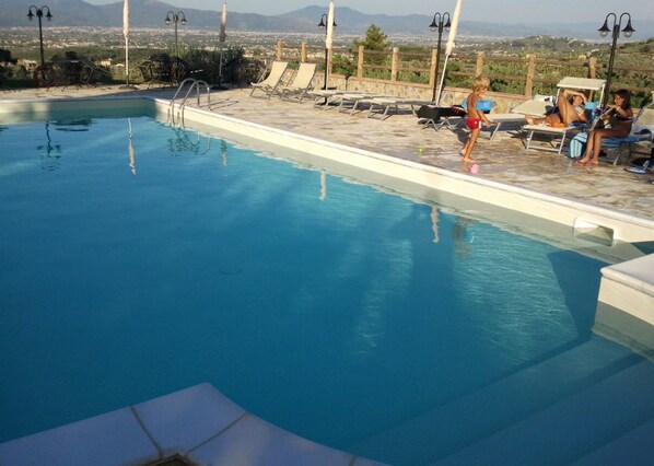 A swimming pool with lounge chairs and a view of distant mountains.