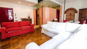 A living room with a red sofa, a white sofa, and a wooden floor. - Bright Apartments Verona - Borsari Historical 1 (Verona)
