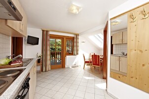 A kitchen with a stove, sink, and wooden cabinets. There is a dining area with a table and chairs.