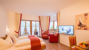 Una habitación de hotel con una cama, dos sillas rojas, un televisor y un frutero.
