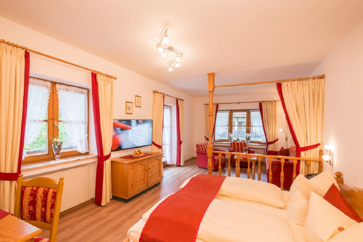 A hotel room with a bed, a TV, a dining table, and curtains.