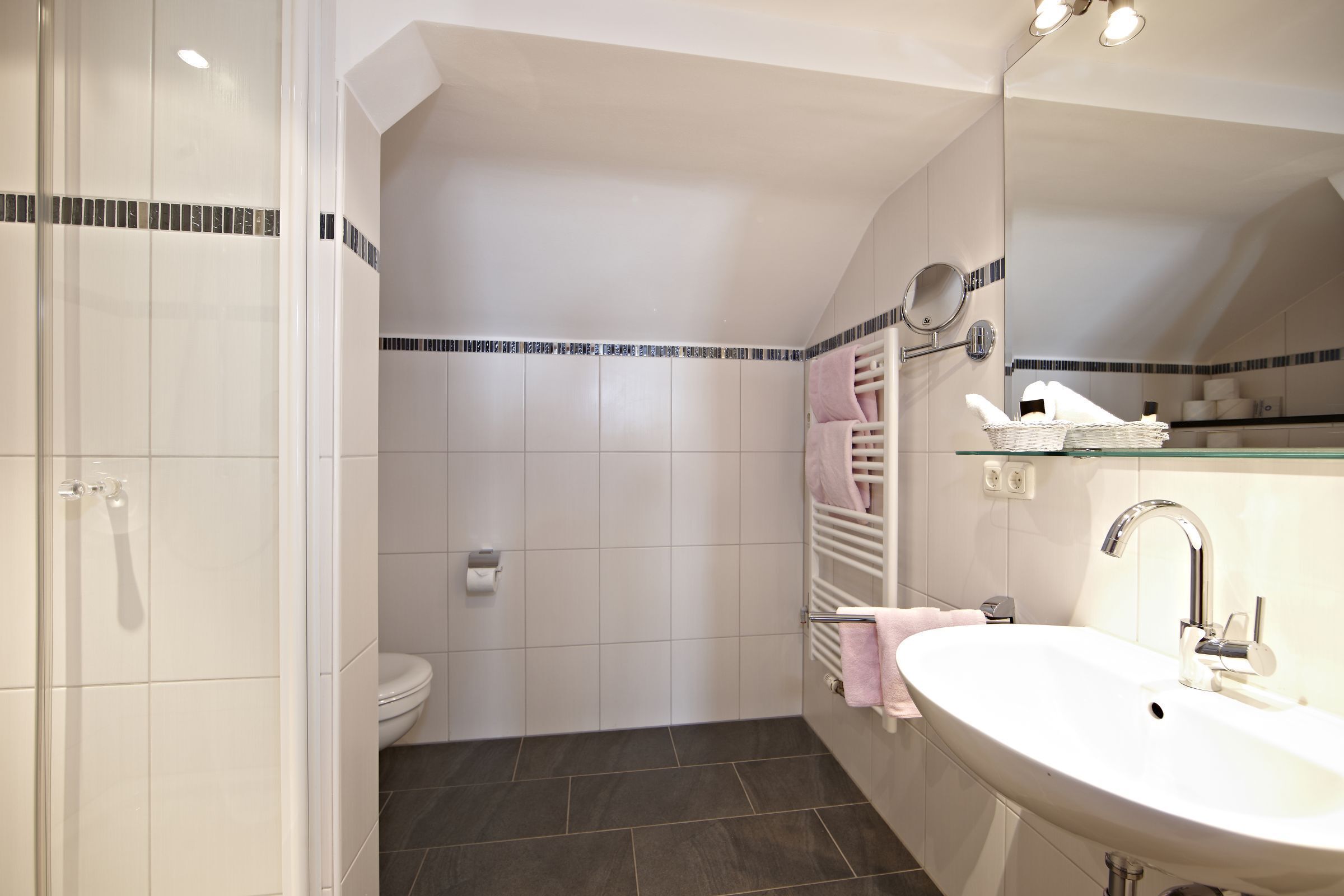 A bathroom with a white sink, mirror, and towel rack.
