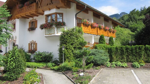 Un edificio de estilo chalete tradicional, con balcones de madera y macetas con flores.