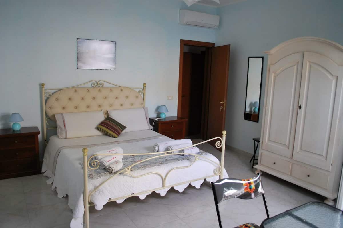 Een slaapkamer met een bed, nachtkastjes, een kledingkast en een spiegel.