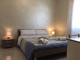 Un dormitorio con cama, mesitas de noche y una silla.