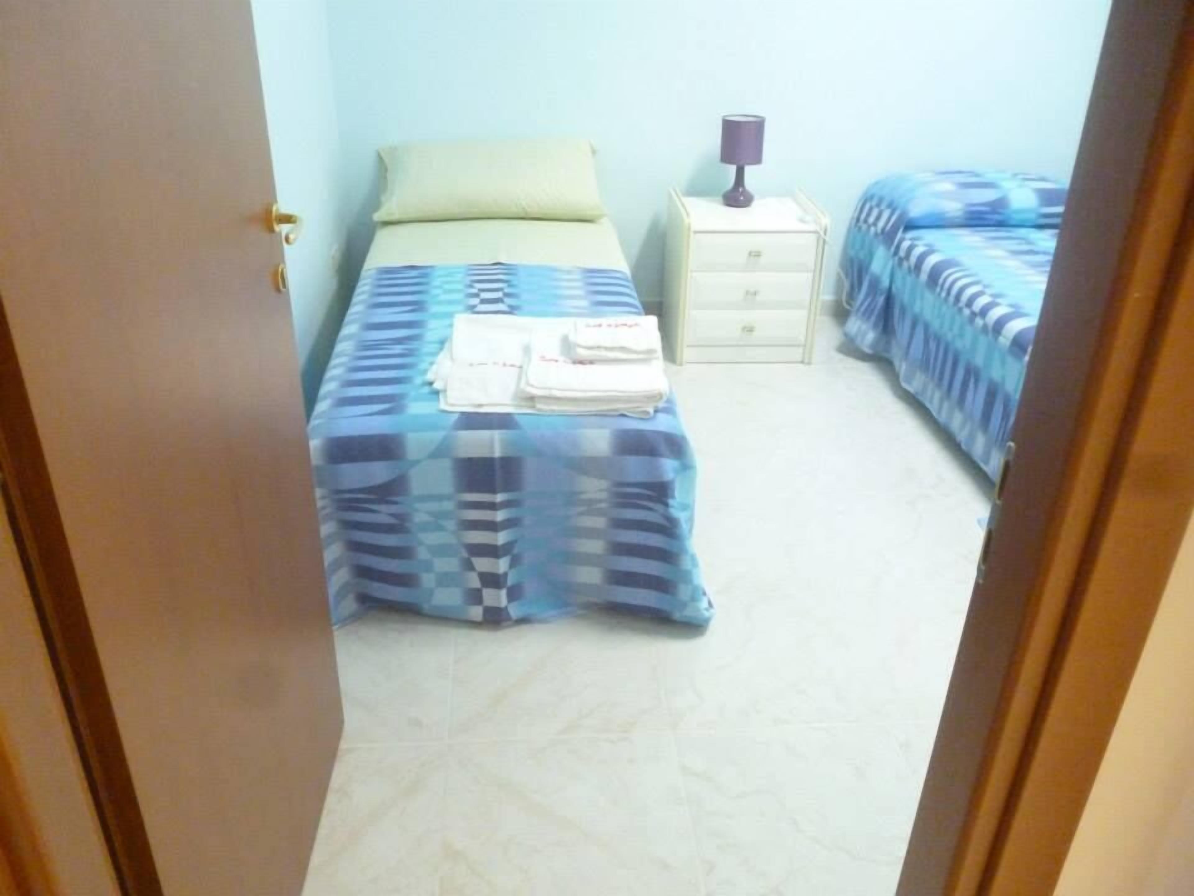 Un dormitorio con dos camas, una mesita de noche y una lámpara.