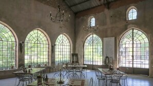 A spacious room with arched windows and a chandelier, featuring a long table and multiple chairs. - Chateau d'Agel (Agel)