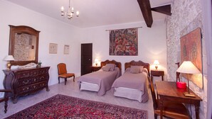 A bedroom with two beds, a dresser, a chair, a rug, and a painting on the wall. - Chateau d'Agel (Agel)