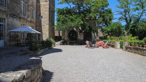 A courtyard with stone walls, a gravel path, and outdoor seating. - Chateau d'Agel (Agel)
