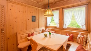 A wooden interior with a dining table, benches, and a hanging light fixture. - Komfort-Ferienhaus Alpspitz (Grainau)