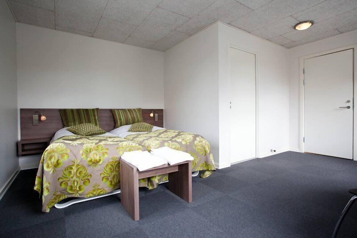 A bedroom with a bed, bedside table, and a door.