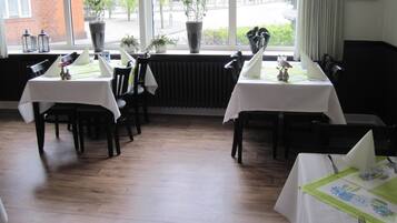 Guests can dine in style with tables set for a meal, surrounded by large windows offering a view of the street outside.