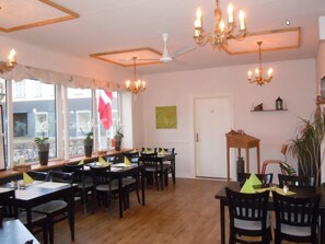 A dining area with multiple tables and chairs, a ceiling fan, and a chandelier. - Turisthotellet (Oksbol)