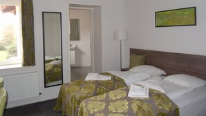 Una habitación de hotel con una cama, un espejo, un cuadro y una ventana con cortinas.