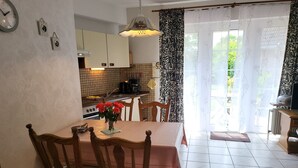 A kitchen with a dining table, chairs, a clock, and a coffee machine.