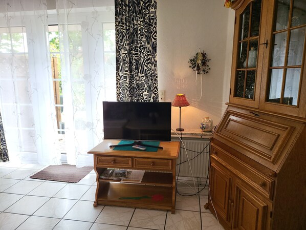 Une pièce comprenant un meuble TV en bois, une lampe et un placard.