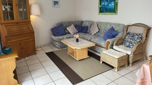 A living room with a sofa, a coffee table, a wicker chair, a cabinet, and a picture on the wall.