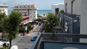 A hotel with a view of the sea, a street with cars, and buildings with balconies.