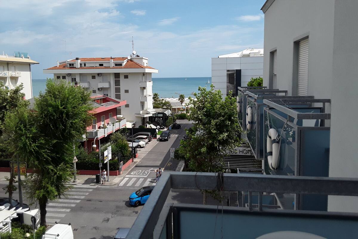 Un hotel con vista sul mare, una strada con auto e edifici con balconi.