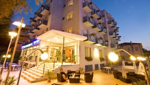 A multi-story hotel with outdoor seating and a covered entrance.