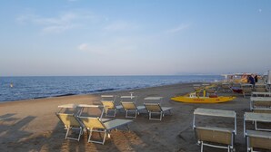 A beach with rows of sun loungers and a yellow emergency boat.