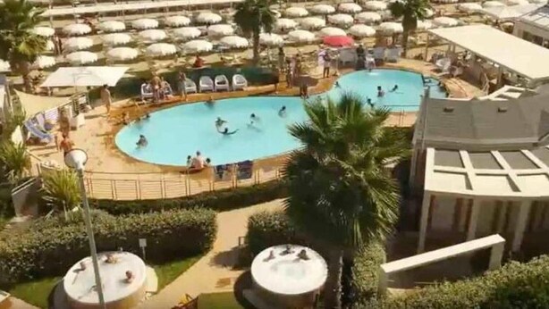 A pool area with multiple swimming pools, lounge chairs, and umbrellas.