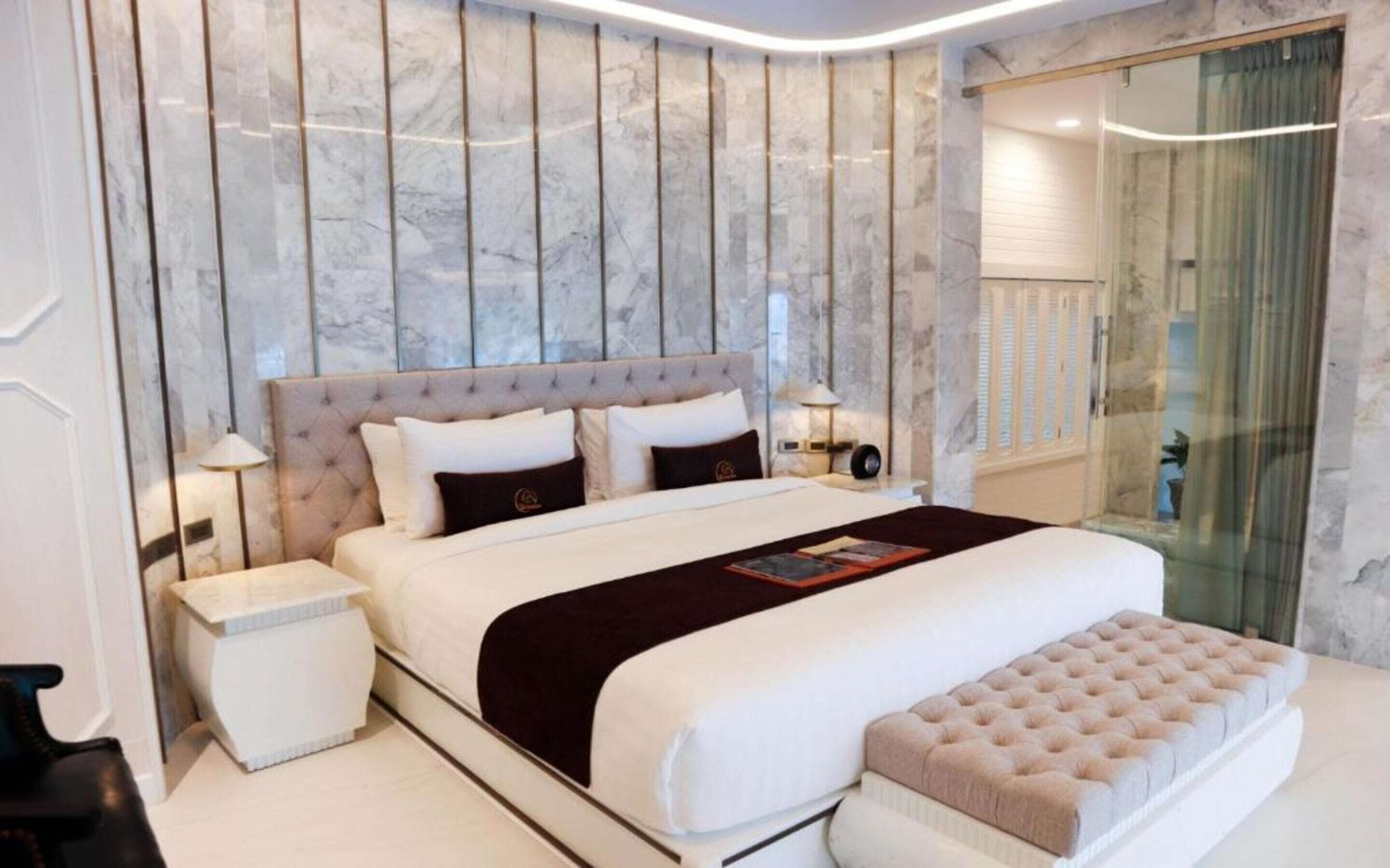 A modern bedroom with a large bed, a bedside table, a nightstand, and a glass shower enclosure.