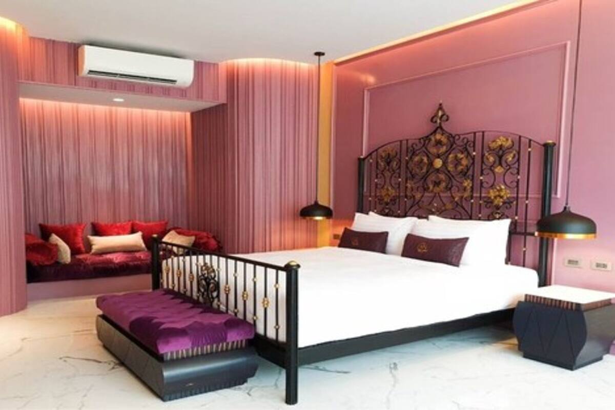 A bedroom with a bed, a bench, a bedside table, and a decorative headboard.