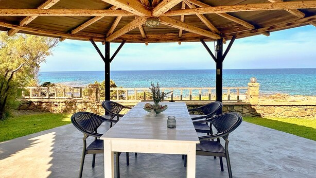 A covered outdoor seating area with a view of the sea, featuring a table and chairs. - Beach front apartment in Leventoxori, Ilias (Leventoxori, Ilias)