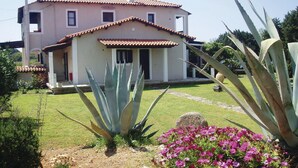 A two-story house with a tiled roof and a small front porch. - Beach front apartment in Leventoxori, Ilias (Leventoxori, Ilias)