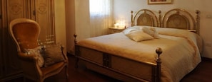 Ein Schlafzimmer mit einem hölzernen Bett, einem Sessel und einem Nachttisch mit Lampe.