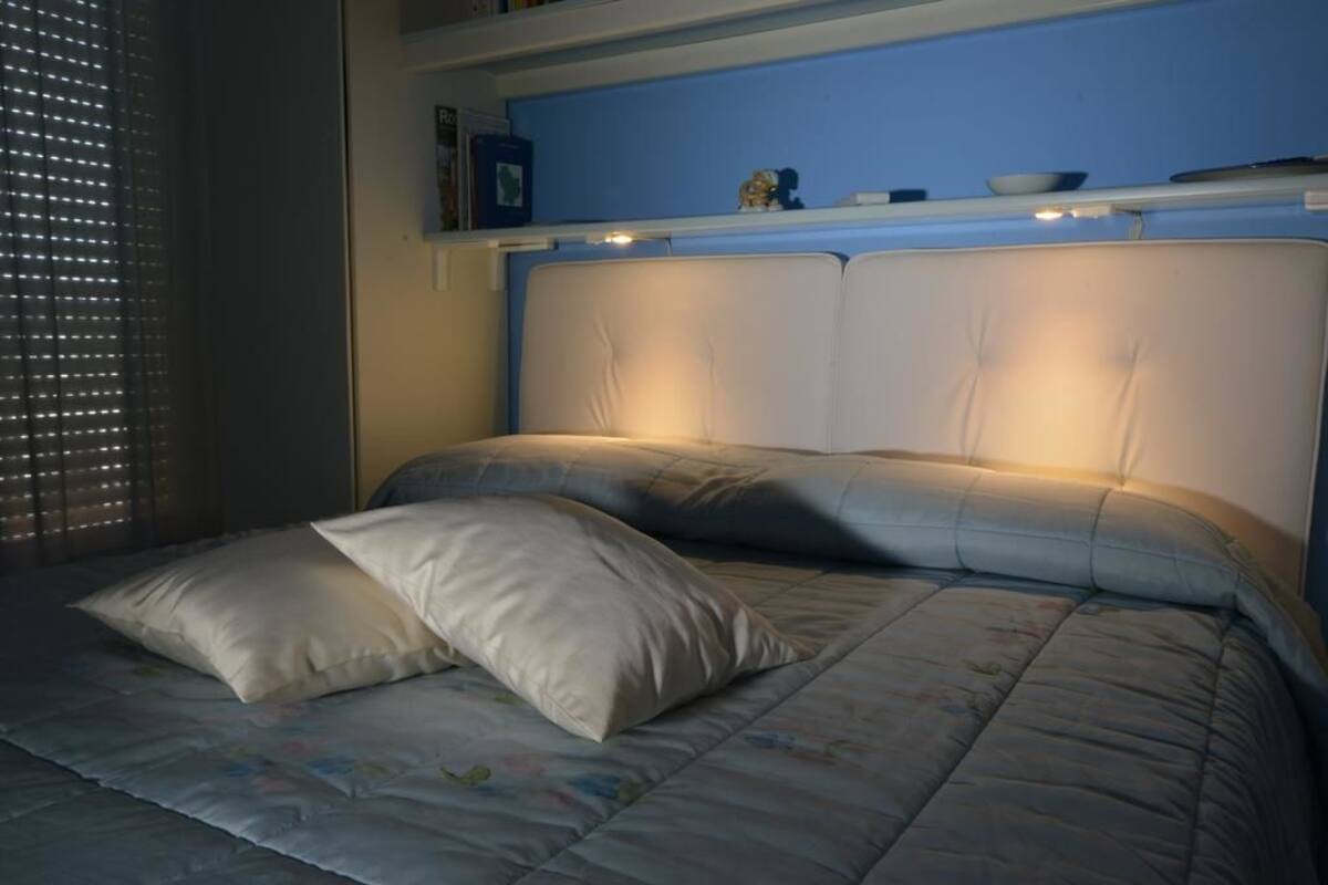 Uma cama com cabeceira, travesseiros e colcha.