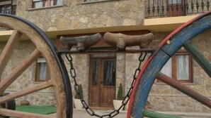 A stone building with a wooden door and a balcony with metal railings. - La Casa de la Pradera (Carrizo)