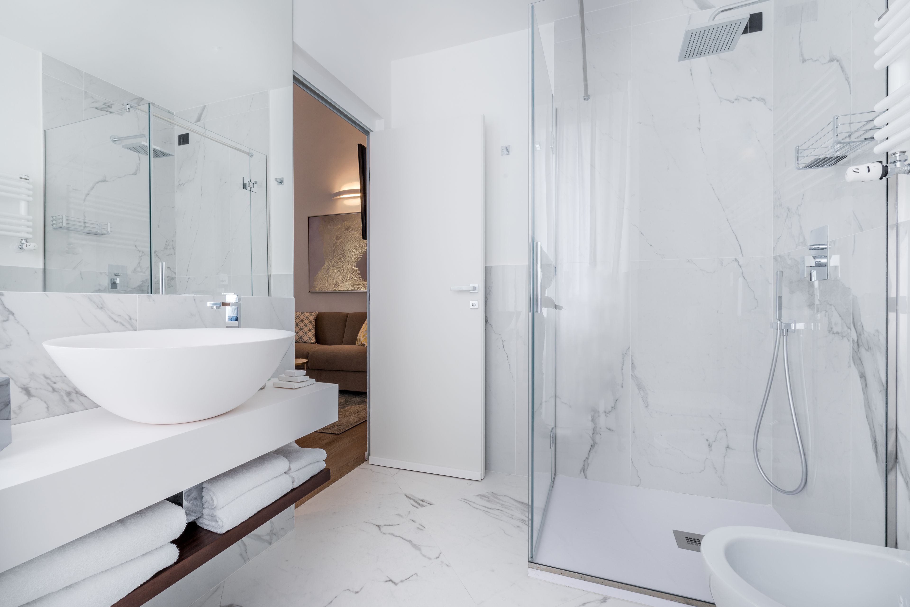 Un baño moderno con un lavamanos grande de color blanco, una ducha con cerramiento de vidrio y una bañera blanca.