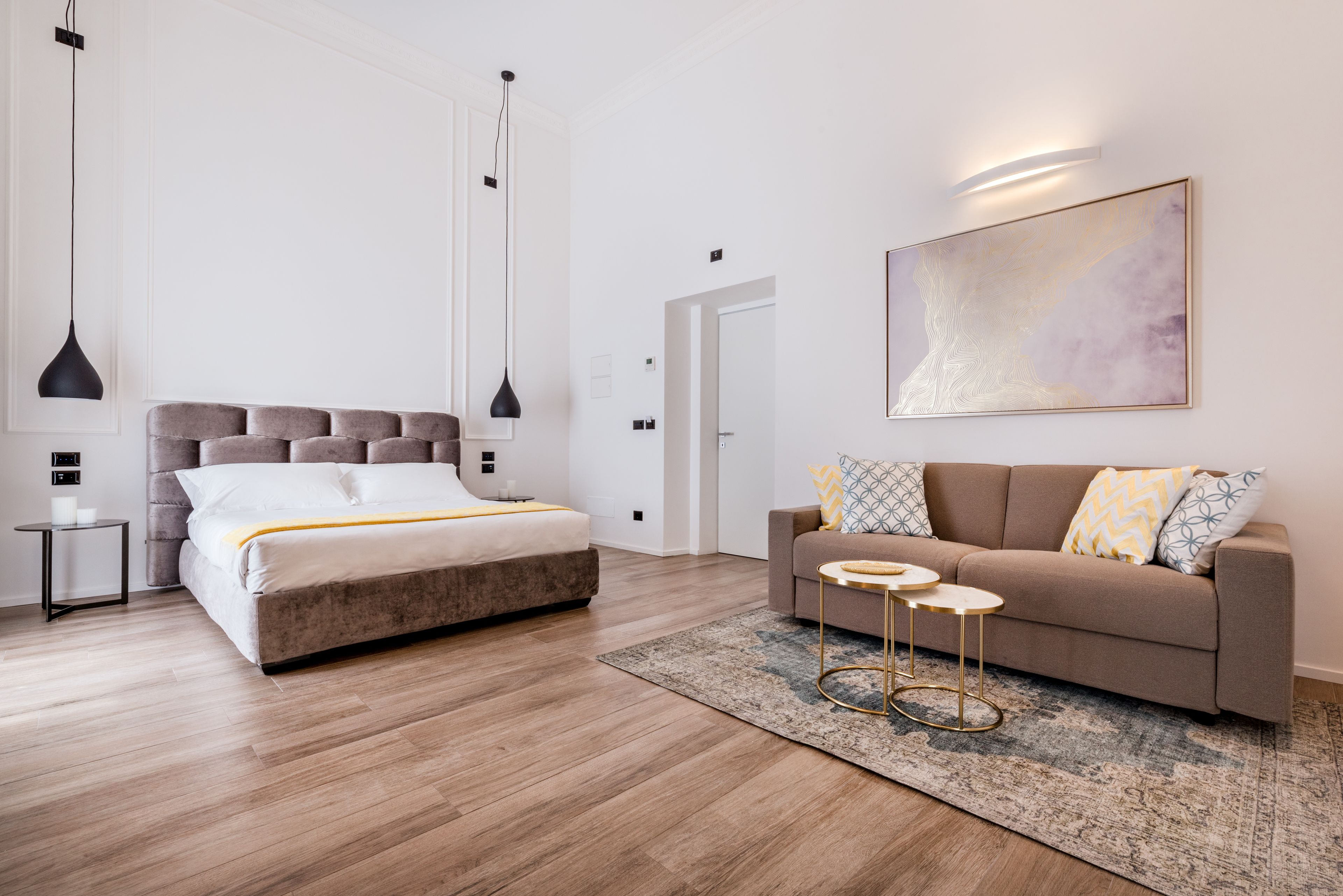 Une chambre à coucher moderne avec un lit, un canapé, une petite table et un tapis.