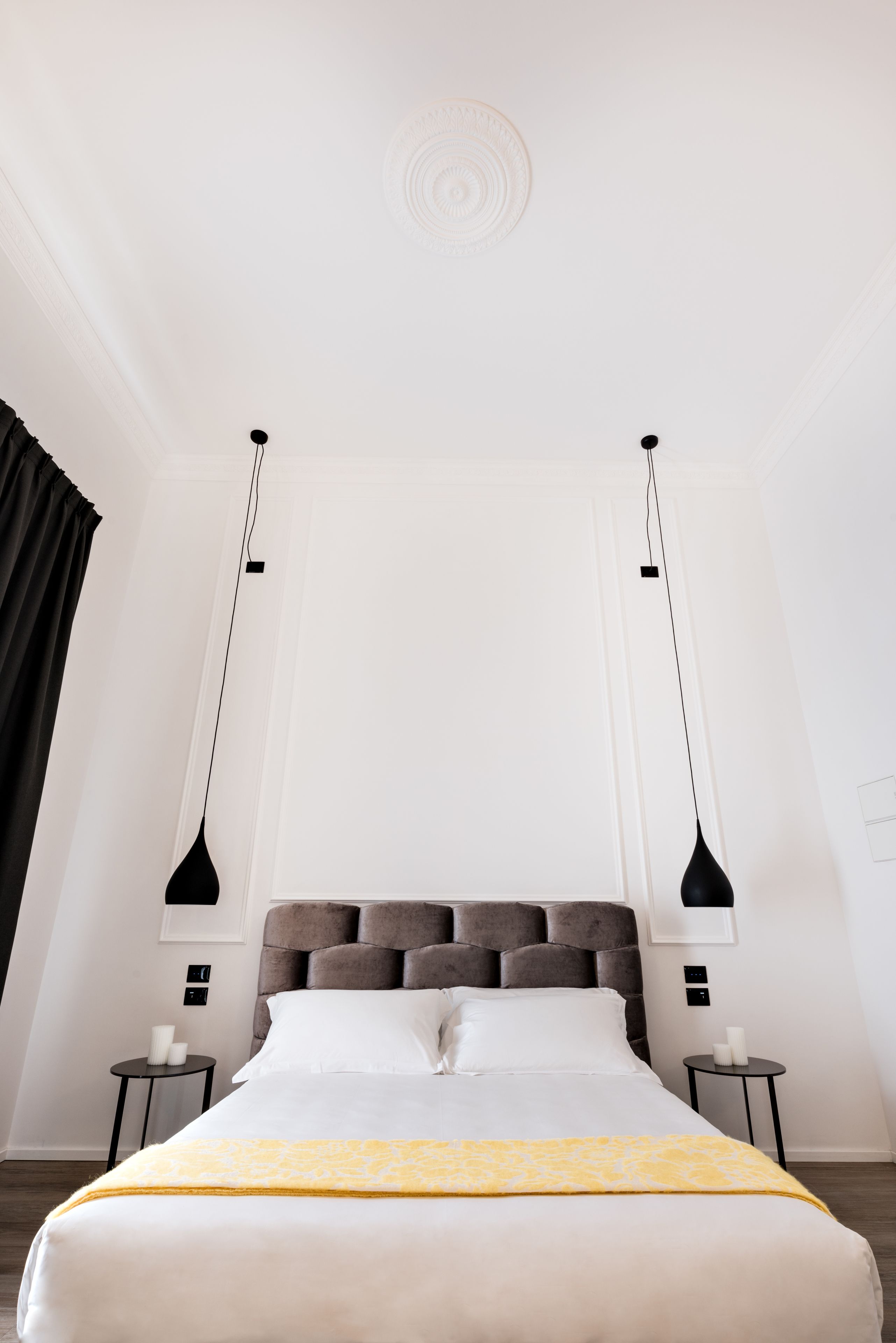 Ein Hotelzimmer mit einem großen Bett, zwei Nachttischen, einer Kopfteil und Pendelleuchten.