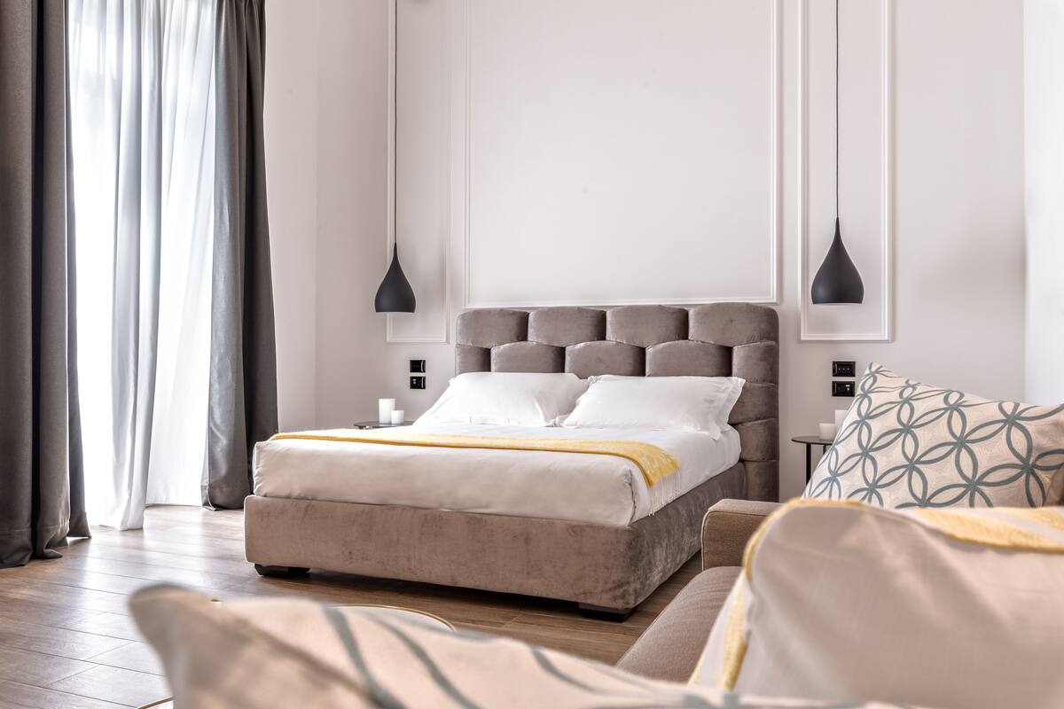 Una camera da letto moderna con un letto grande, due comodini, una lampada da comodino e una finestra con tende.