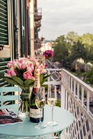 Una mesa con una botella de Moët & Chandon, una copa de champán y un ramo de flores rosas en un balcón.