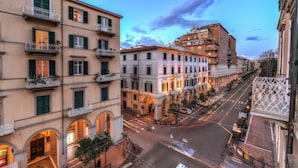 A multi-story building with balconies, arched doorways, and a street view.
