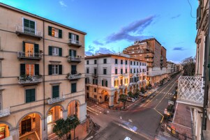 Un edificio de varios pisos con balcones, arcos y vista a la calle.