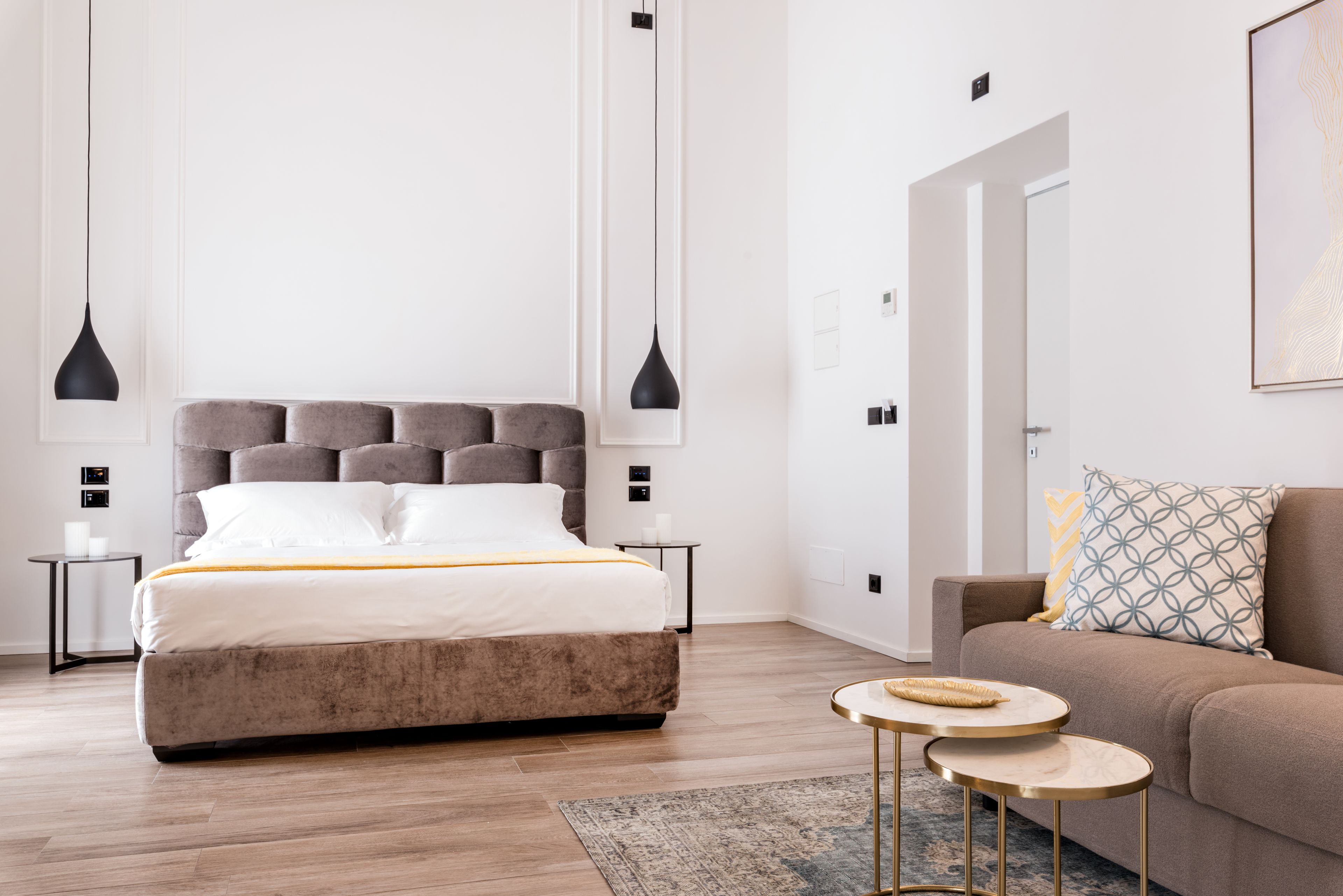 Ein modernes Schlafzimmer mit einem großen Bett, zwei Nachttischen, einem Sofa und einem kleinen runden Tisch.