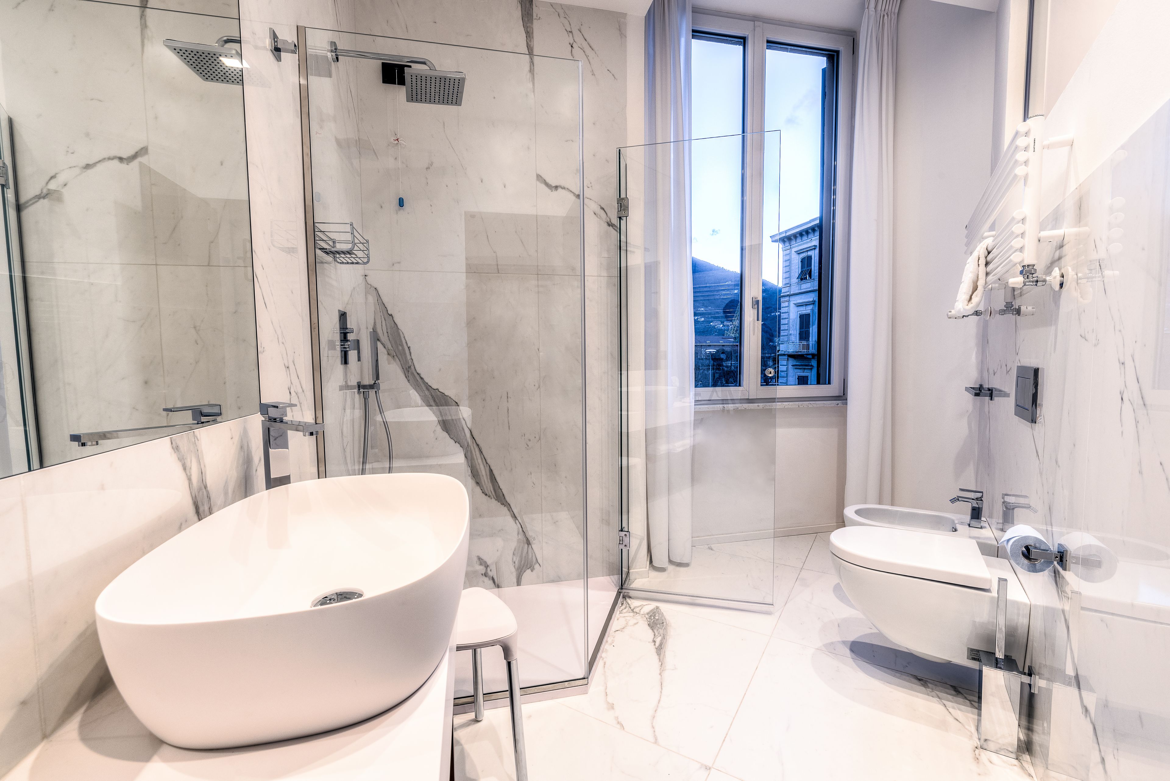 Un baño moderno con un lavamanos ovalado grande, una ducha con cerramiento de vidrio y una bañera.