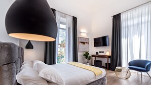 A modern hotel room with a large bed, a desk, a TV, and a view of the outdoors.