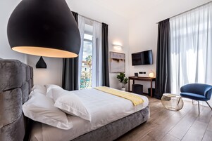 A modern hotel room with a large bed, a desk, a TV, and a view of the outdoors.