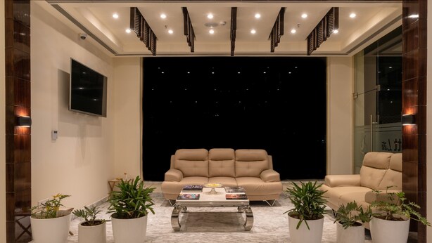 A modern living room with a beige sofa, a coffee table, and potted plants. - Cygnett Lite (Alwar)