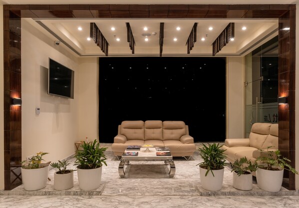 A modern living room with a beige sofa, a coffee table, and potted plants. - Cygnett Lite (Alwar)