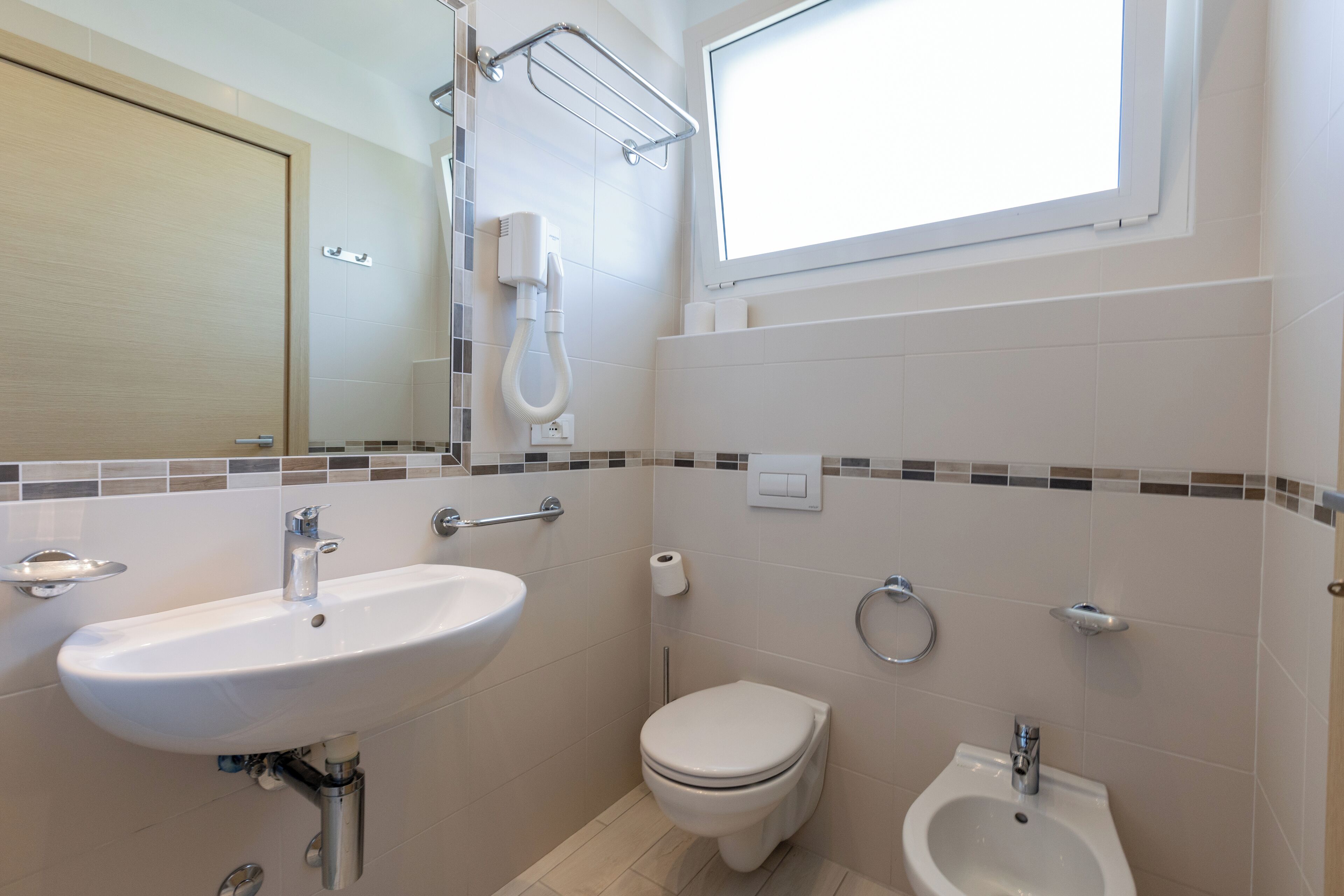 Un baño con lavabo, inodoro, bidé y ventana.