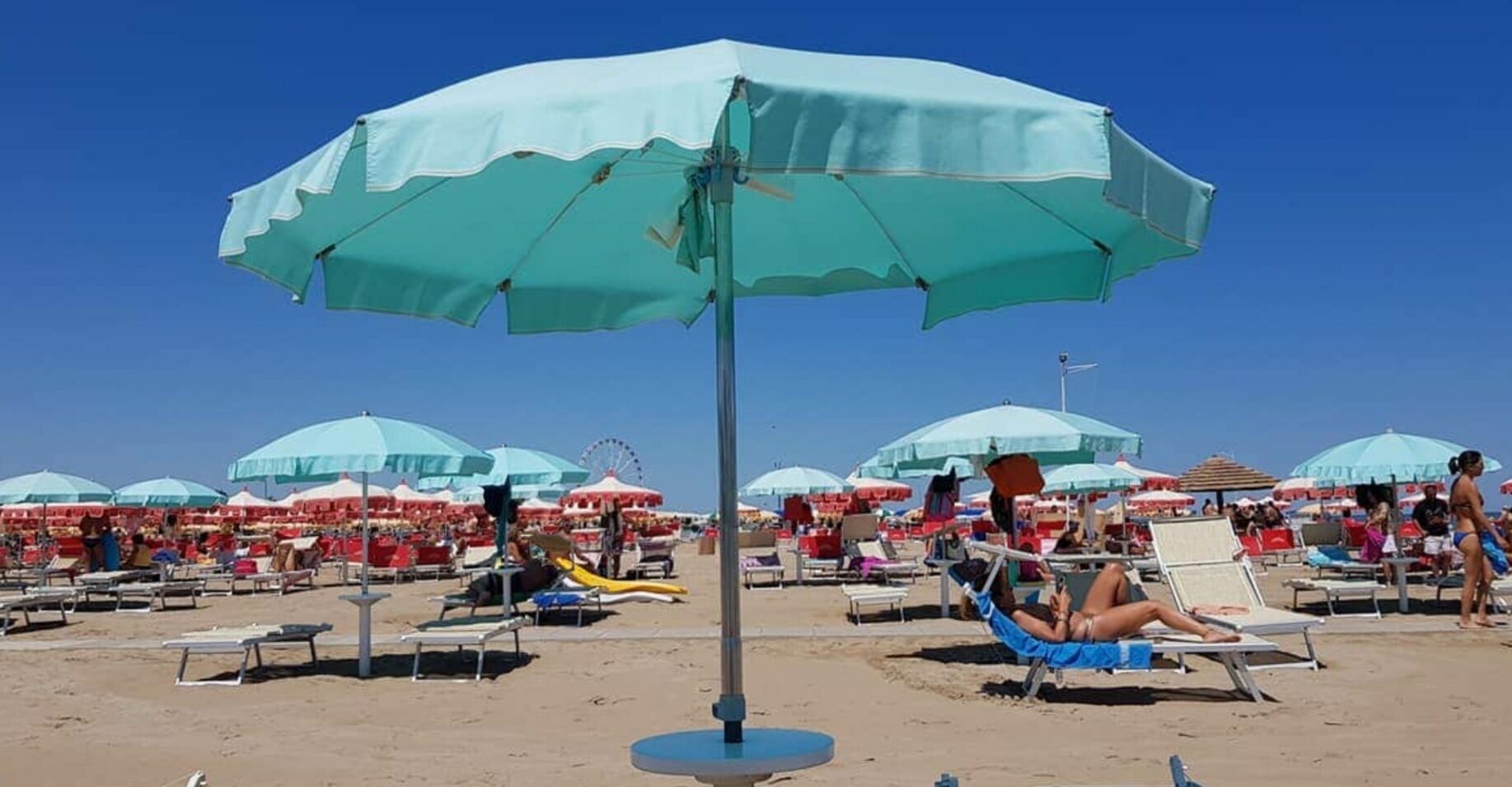 A beach with multiple umbrellas and sun loungers.