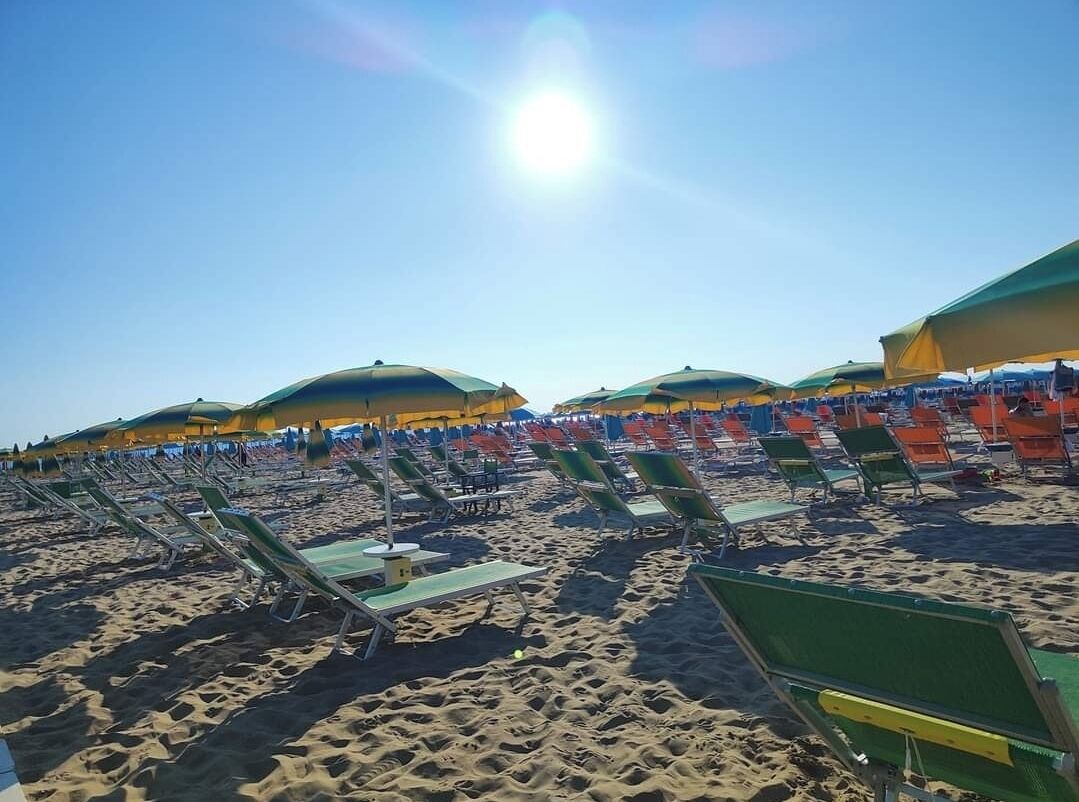 A beach with rows of sun loungers and umbrellas.