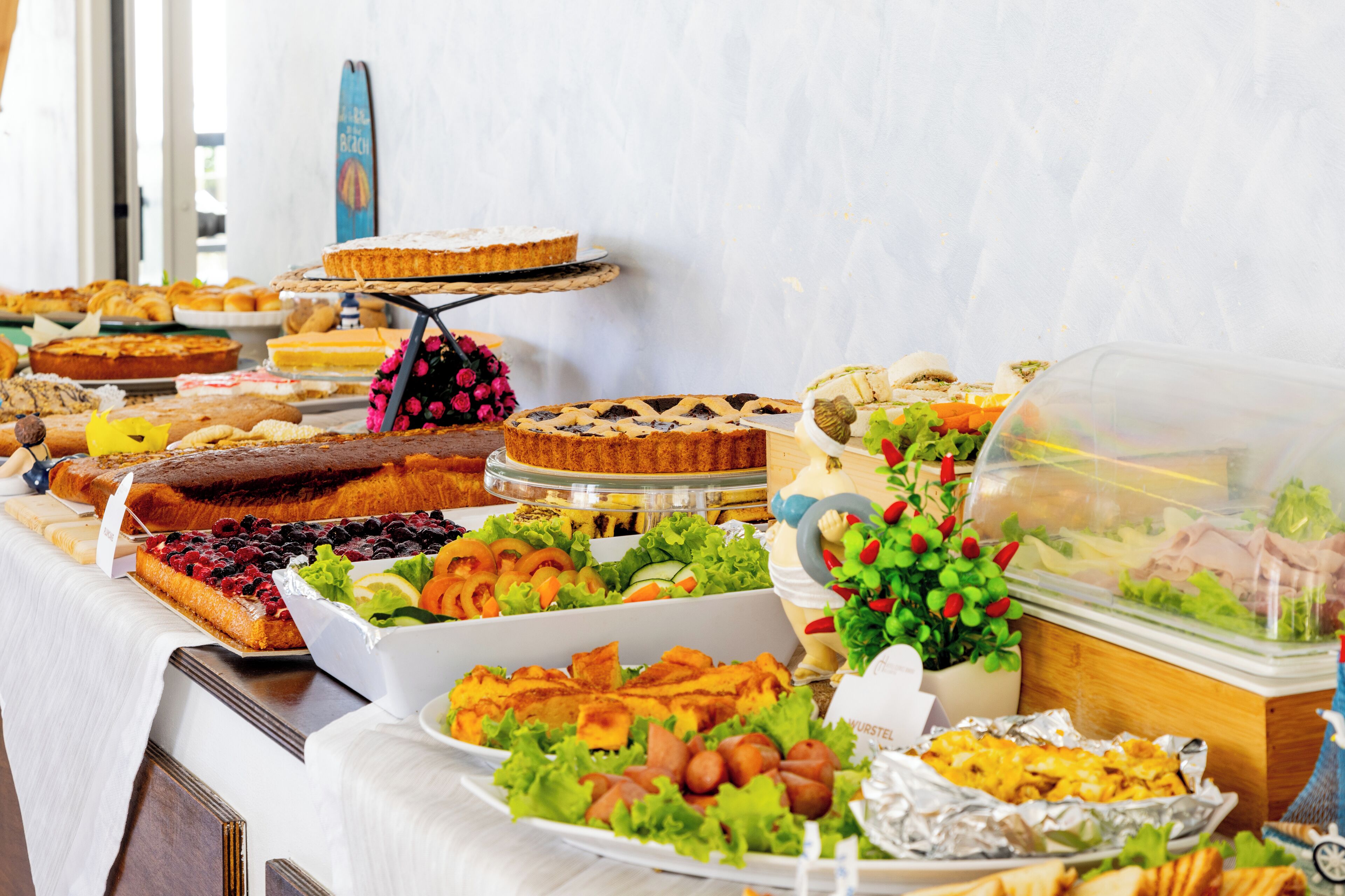 A buffet with various dishes including pies, salads, and sandwiches.